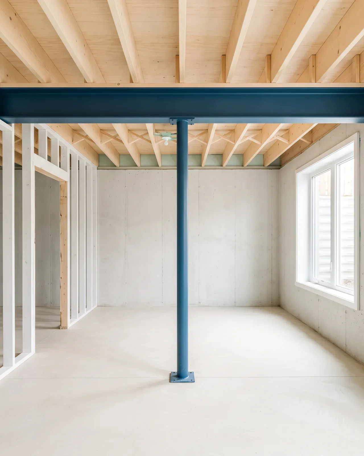 Basement with a new blue steel beam on a slim post under new joists