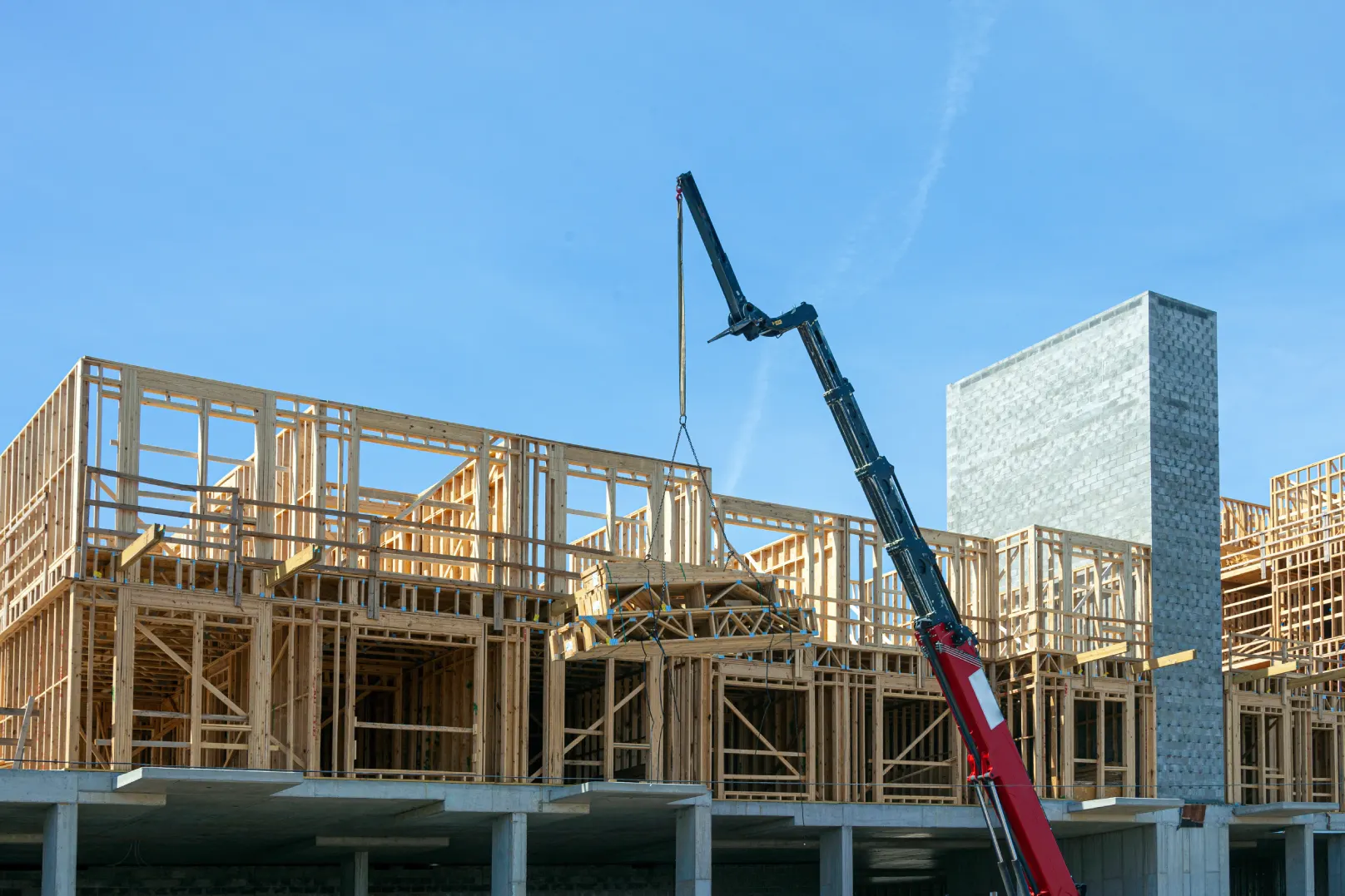 Wood-frame townhouse block under construction with a crane overhead