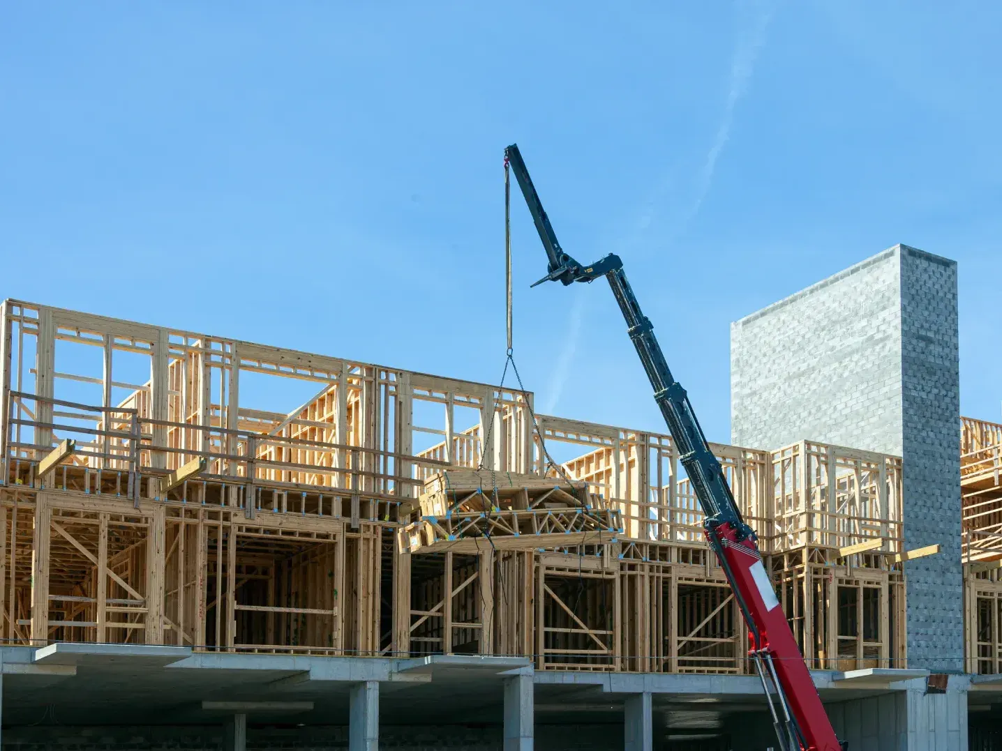 Wood-frame townhouse block under construction with a crane overhead